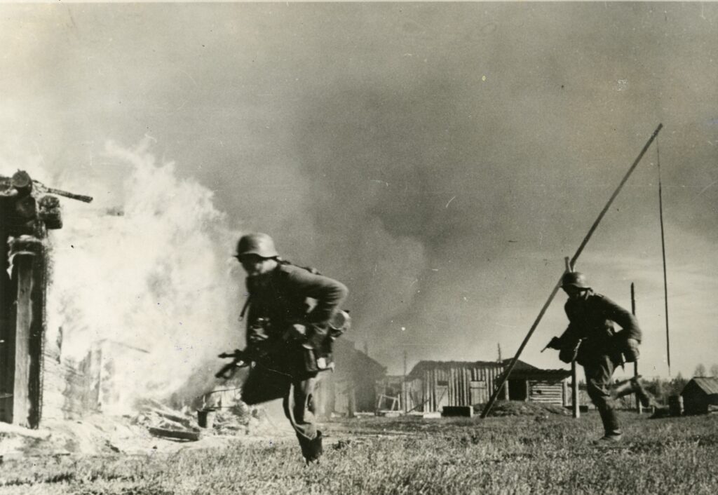 Fotografia storica di soldati che corrono tra il fumo e le fiamme