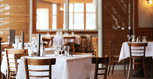 Sala di un ristorante con tavoli apparecchiati e tovaglie bianche