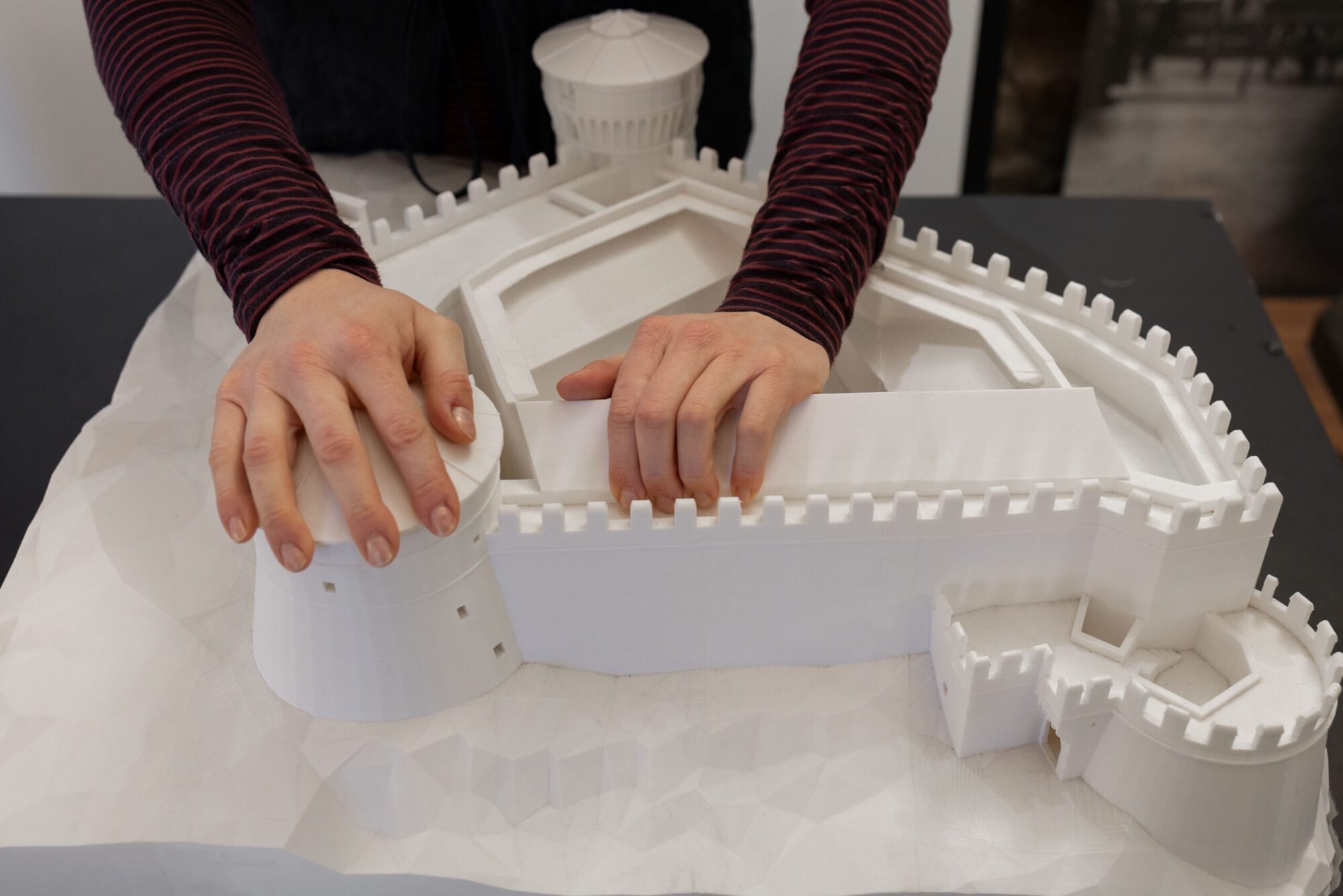 Mani che esplorano il plastico tattile bianco del Castello di Rovereto