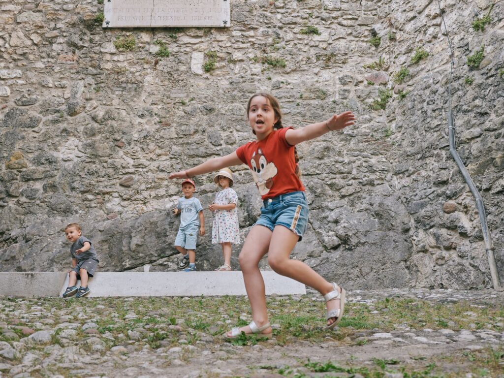 Bambina gioca a braccia aperte nel cortile del castello