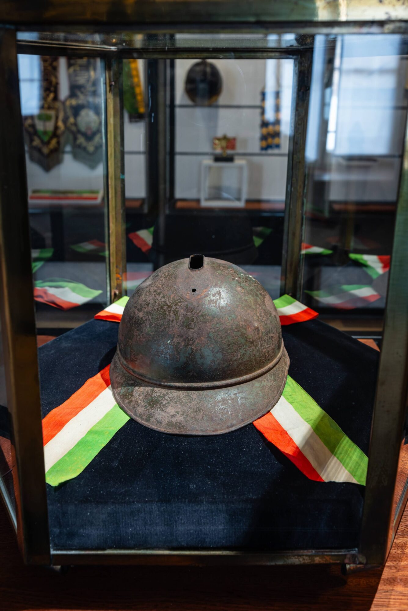 Elmetto Adrian mod. 1915 legato alla storia del Milite Ignoto, in vetrina sul tricolore