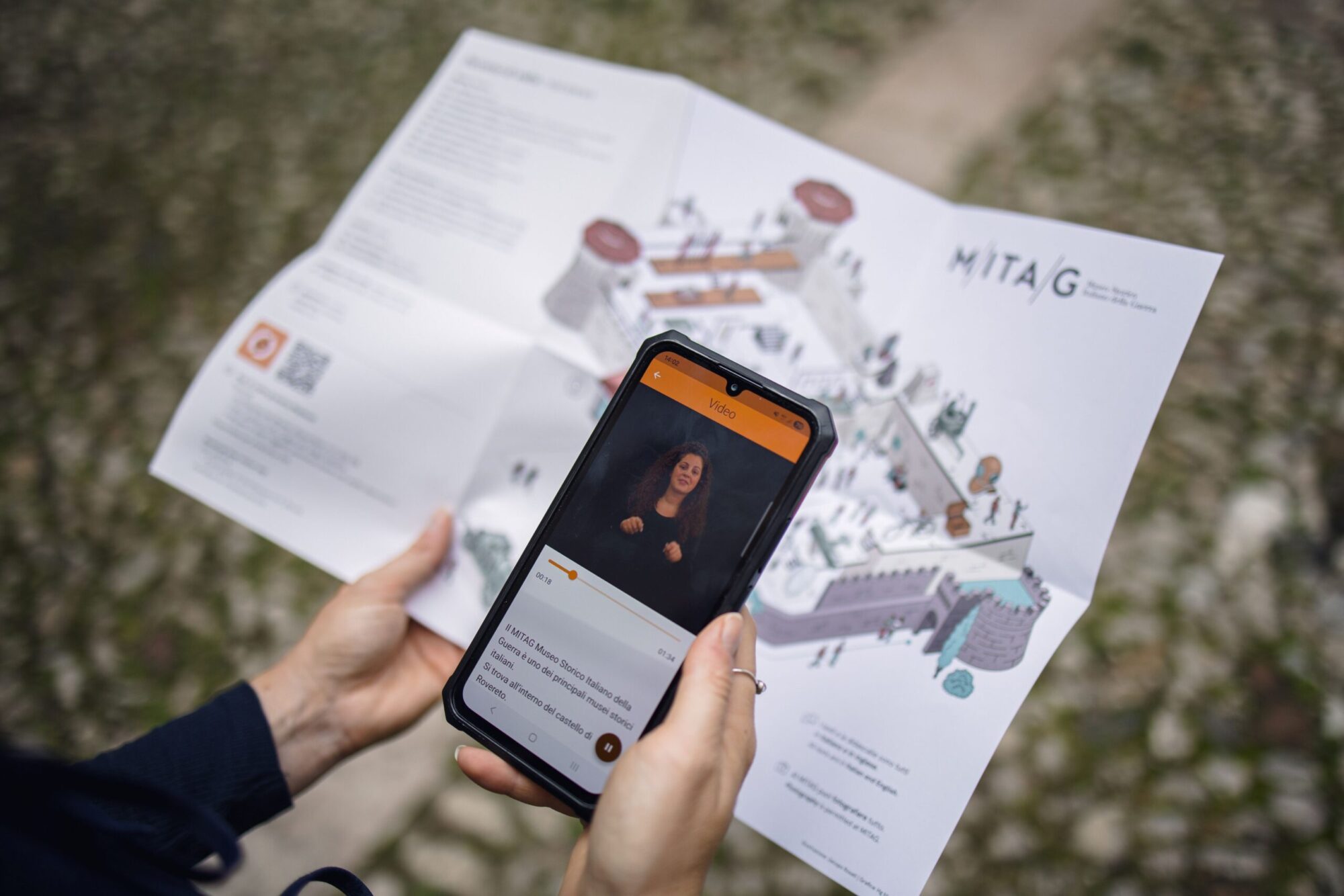 Visitatore con la mappa del MITAG e lo smartphone con la videoguida in LIS