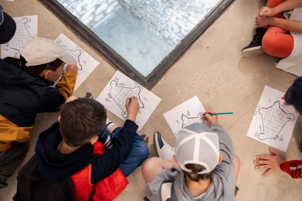 Bambini disegnano seduti per terra durante un'attività al museo