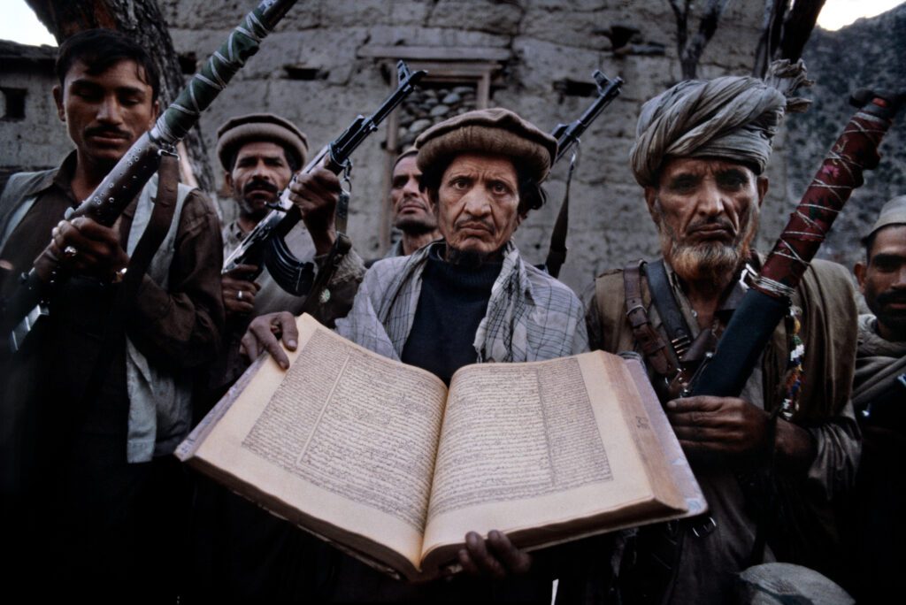 Fotografia di Francesco Cito: combattenti afghani armati con un libro aperto, 1980