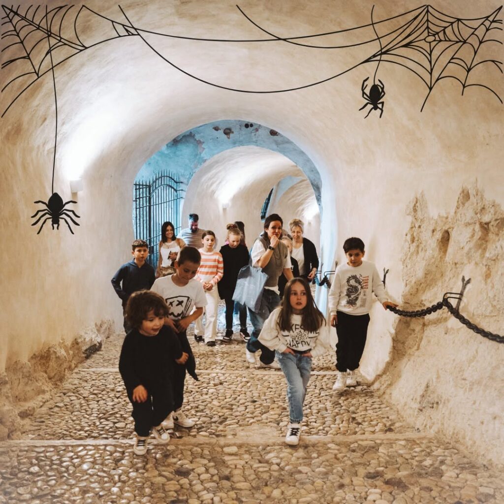 Bambini corrono in un cunicolo del castello decorato con ragnatele per la caccia ai fantasmi