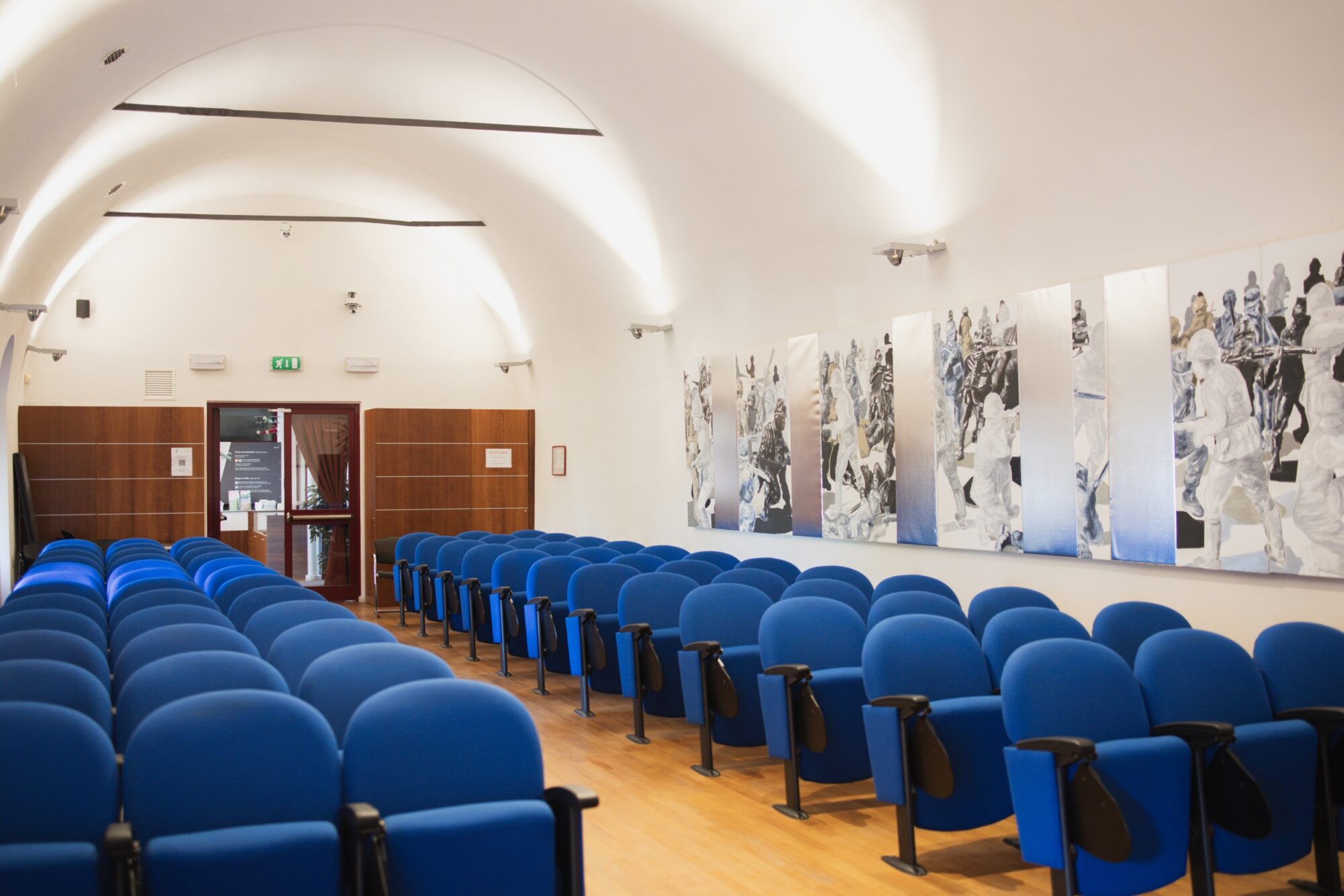Sala Conferenze del MITAG con poltroncine blu e fotografie storiche alle pareti