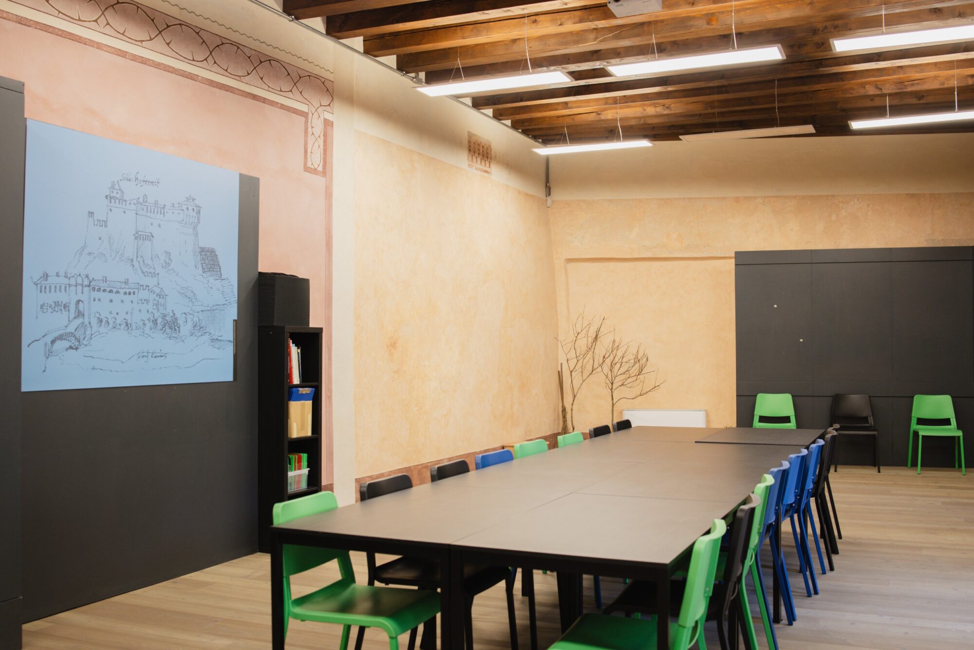 Sala per riunioni e laboratori con lungo tavolo e sedie colorate