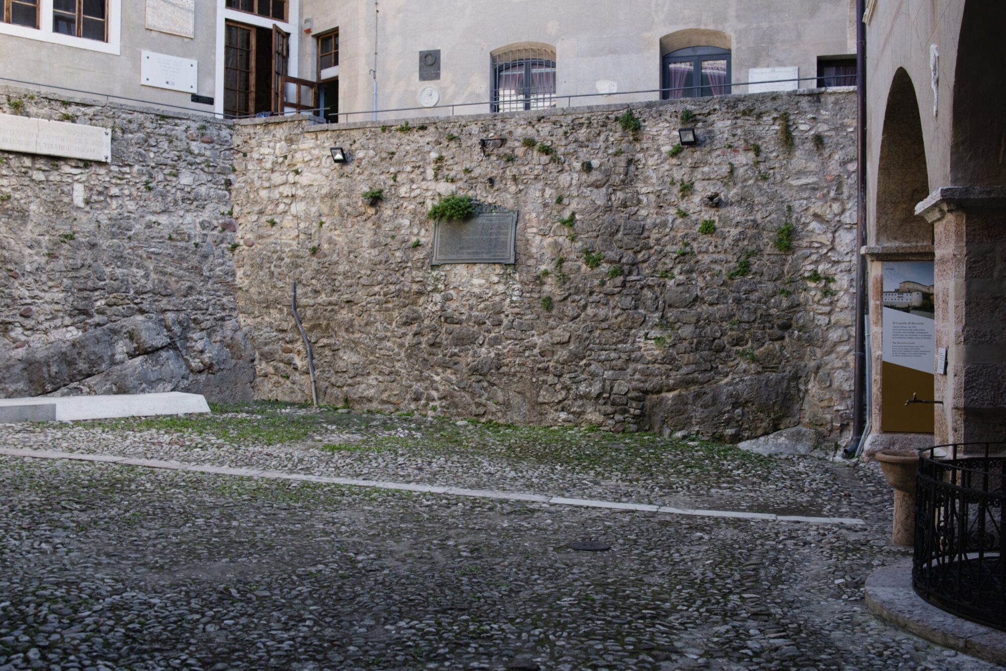 Cortile interno del castello con muro in pietra e prato