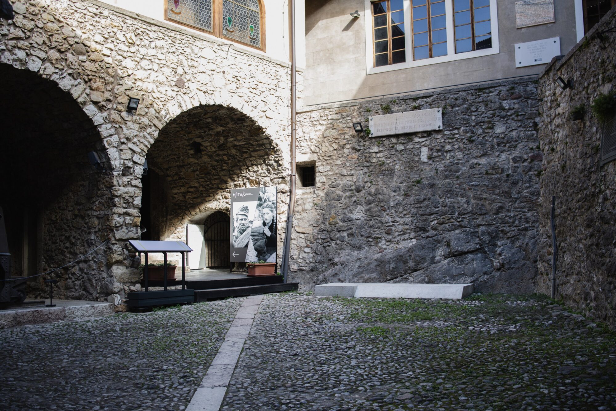 Cortile del castello con archi in pietra e un palco allestito